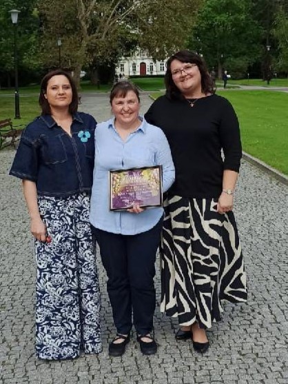 3 naukowczynie z naszego wydziału stoją w odświętnych ubraniach na tle rektoratu SGGW. W środku Pani Elżbieta Hać-Szymańczuk z dyplomem przyznanym w konkursie samorządu studentów SGGW